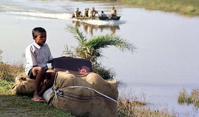 A boy waits with all of his belongings for a rescue boat to take him back home through a water logged area near Balasore, Odisha, as river water flooded her village among thousands of others due to the cyclone that hit eastern India. (AFP Photo)