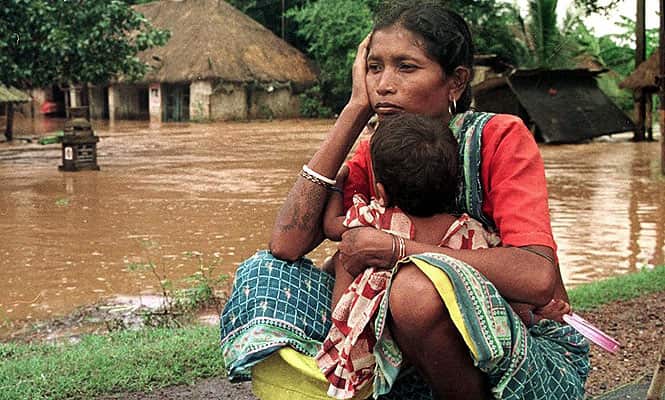 A woman sits along with her child despondently on dry land waiting for relief to come as her home lies submerged in flood waters 31 October 1999 near Balasore in Orissa, as river water flooded her village among thousands of others due to the cyclone that hit eastern India. (AFP Photo)