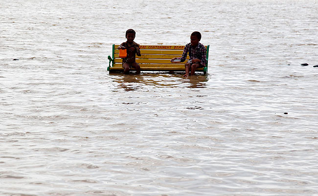 Boys play as they sit on a bench at the flooded banks of the river Ganges after rains in Allahabad. REUTERS Boys play as they sit on a bench at the flooded banks of the river Ganges after rains in Allahabad. REUTERS