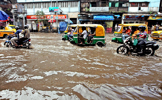 Vehicles pass through a waterlogged street after heavy rains in Kolkata. PTI Photo Vehicles pass through a waterlogged street after heavy rains in Kolkata. PTI Photo