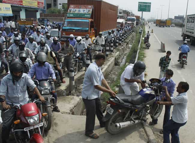 People are forced to lift their bikes and cross over across the main carriageway in Gurgaon, as service roads remain clogged with traffic and sewage. (Manoj Kumar/ HT Photo) People are forced to lift their bikes and cross over across the main carriageway in Gurgaon, as service roads remain clogged with traffic and sewage. (Manoj Kumar/ HT Photo)