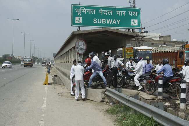 People are forced to lift their bikes and cross over across the main carriageway in Gurgaon, as service roads remain clogged with traffic and sewage. (Manoj Kumar/ HT Photo) People are forced to lift their bikes and cross over across the main carriageway in Gurgaon, as service roads remain clogged with traffic and sewage. (Manoj Kumar/ HT Photo)
