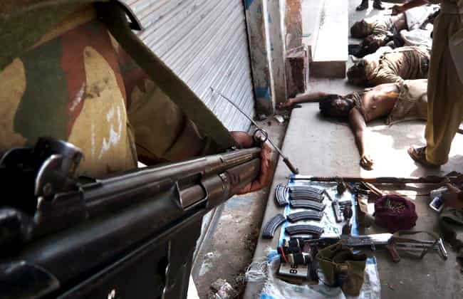 In this August 11, 2009 photo, Pakistani security force members stand near weapons they took from militants after a shootout which killed four militants, top right, in Kabal, in the Swat valley of Pakistan. (AP Photo/Naveed Ali, File)