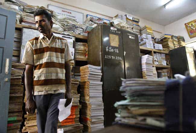 In this Dec. 10, 2012 photo, a man stands amid piles of documents of land records inside a room at the government registrar's office in Hoskote 30 Kilometers (19 miles) from Bangalore in southern Indian state of Karnataka. For years, Karnataka's land records were a quagmire of disputed, forged documents maintained by thousands of tyrannical bureaucrats who demanded bribes to do their jobs. In 2002, there were hopes that this was about to change. Photo: AP/Aijaz Rah) In this Dec. 10, 2012 photo, a man stands amid piles of documents of land records inside a room at the government registrar's office in Hoskote 30 Kilometers (19 miles) from Bangalore in southern Indian state of Karnataka. For years, Karnataka's land records were a quagmire of disputed, forged documents maintained by thousands of tyrannical bureaucrats who demanded bribes to do their jobs. In 2002, there were hopes that this was about to change. Photo: AP/Aijaz Rah)