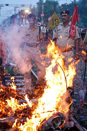 Railway policemen stand near a burning effigy representing the government during a protest along railway tracks in Allahabad. AP Photo