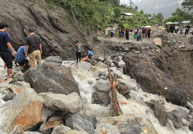 In this handout photograph received from the Sikkim Information and Public Relation Department (IPR) onlookers watch as rescue work following landslides caused by flash floods takes place on the Mongon – Chungthang road, some 30 kms north of the Gangtok. (AFP PHOTO) 
</div)