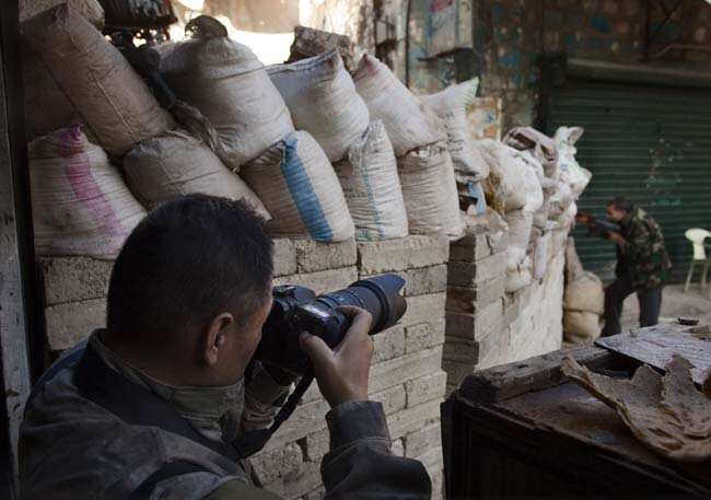 Japanese trucker Toshifumi Fujimoto (L) takes pictures of a rebel fighter behind sandbags on the green line in Aleppo's old city on December 27, 2012. Photo: AFP/ST) Japanese trucker Toshifumi Fujimoto (L) takes pictures of a rebel fighter behind sandbags on the green line in Aleppo's old city on December 27, 2012. Photo: AFP/ST)