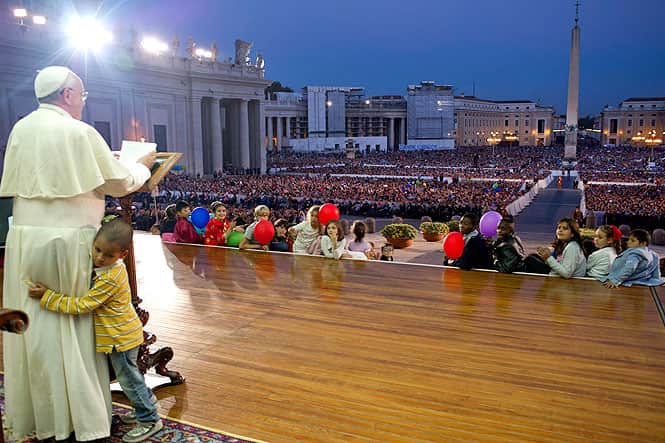 In this photo provided by the Vatican newspaper L'Osservatore Romano, Pope Francis touches a boy's head, no name available, as he delivers his speech during an audience with families in St Peter's Square gathered for the Pontifical Council for the Familyís plenary assembly, at the Vatican.AP photo