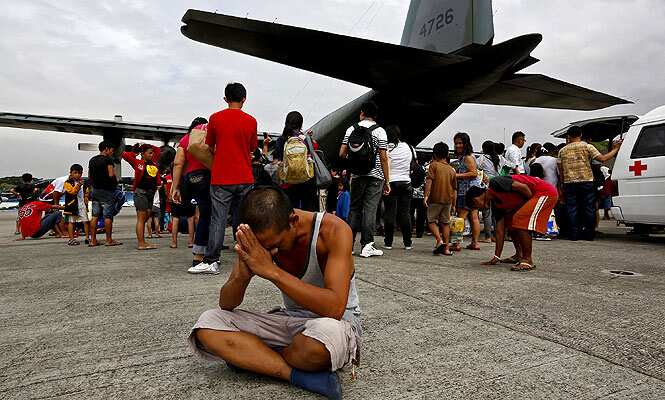A survivor from Tacloban, which was devastated by Typhoon Haiyan gestures while sitting on the ground after disembarking a Philippine Air Force C-130 aircraft at the Villamor Airbase, in Manila, Philippines. (AP photo)</em>
</div) A survivor from Tacloban, which was devastated by Typhoon Haiyan gestures while sitting on the ground after disembarking a Philippine Air Force C-130 aircraft at the Villamor Airbase, in Manila, Philippines. (AP photo)</em>
</div)