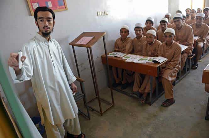 An Afghan teacher writes on a whiteboard as he teaches English to orphans at the Shiekh Zayed orphanage in Kandahar. (AFP Photo)
</div) An Afghan teacher writes on a whiteboard as he teaches English to orphans at the Shiekh Zayed orphanage in Kandahar. (AFP Photo)
</div)