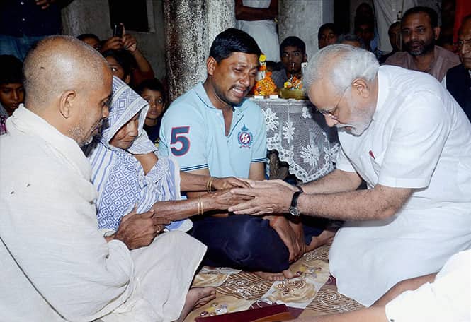 BJP's prime minister candidate Narendra Modi consoles the family members of Rajnarain Singh, a victim of the recent serial bomb blasts, in Patna. (PTI Photo) 
</div)
