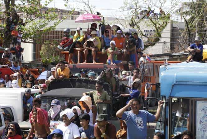Typhoon survivors and rescuers watch a live telecast of the WBO international welterweight being match between the Philippines' Manny Pacquiao and American Brandon Rios at a public park in Tacloban city. (AP Photo)</em> 
</div)