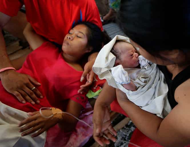 New-born baby Bea Joy is held as mother Emily Ortega, 21, rests after giving birth at an improvised clinic at Tacloban airport in Tacloban. (AP photo)</em) New-born baby Bea Joy is held as mother Emily Ortega, 21, rests after giving birth at an improvised clinic at Tacloban airport in Tacloban. (AP photo)</em)