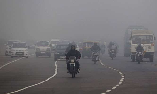 Traffic moves on a road amidst fog in New Delhi. (PTI)</font></em></strong)