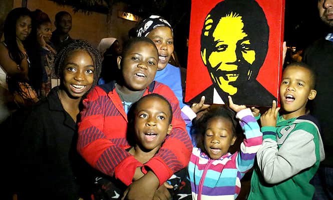 South Africans hold pictures of former South African president Nelson Mandela as they pay tribute following his death in Johannesburg. (AFP Photo)
</div) South Africans hold pictures of former South African president Nelson Mandela as they pay tribute following his death in Johannesburg. (AFP Photo)
</div)