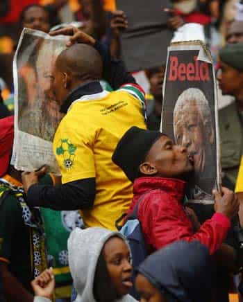 People kiss images of late Nelson Mandela as they arrive for a mass memorial at FNB Stadium in Johannesburg. (Reuters photo)</strong>
</div) People kiss images of late Nelson Mandela as they arrive for a mass memorial at FNB Stadium in Johannesburg. (Reuters photo)</strong>
</div)