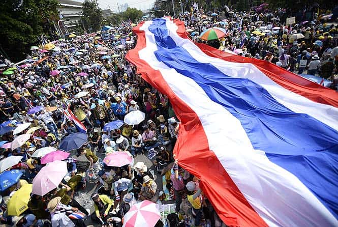 Anti-government protesters unveil a large Thai flag as they descend on Government House in Bangkok. (Reuters photo) 
</div)