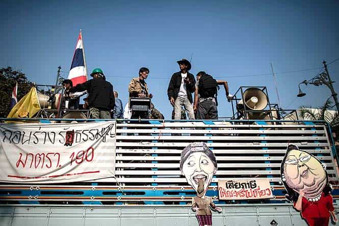 Demonstrators stand on a truck next to the government building in Bangkok. (AFP photo) 
</div)