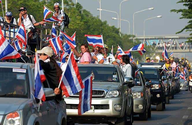 Thai anti-government protesters wave national flags as they rally during a demonstration at Government Complex in Bangkok. (AFP photo) 
</div)