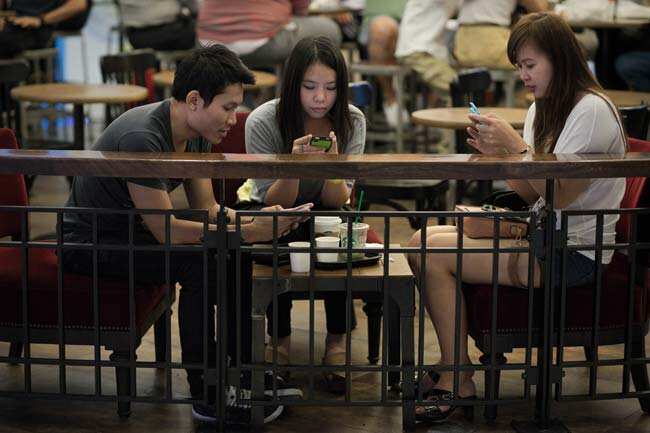 A picture showing friends looking at their smartphones at a coffee shop in a shopping mall in Bangkok. Photo: AFP/ Nicolas Asfouri A picture showing friends looking at their smartphones at a coffee shop in a shopping mall in Bangkok. Photo: AFP/ Nicolas Asfouri