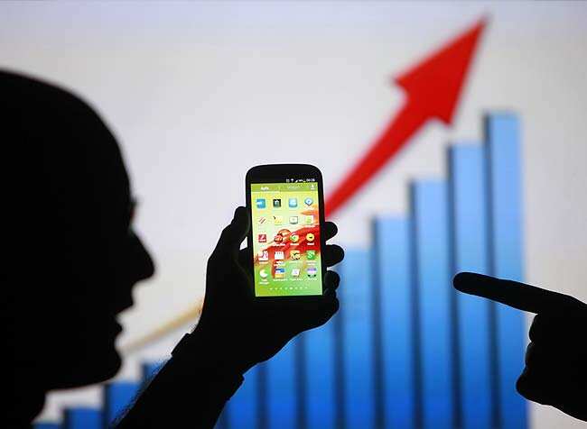 Men are silhouetted against a video screen with as they pose with a Samsung Galaxy S3 smartphone in this photo illustration taken in the central Bosnian town of Zenica. Photo: Reuters/Dado Ruvic