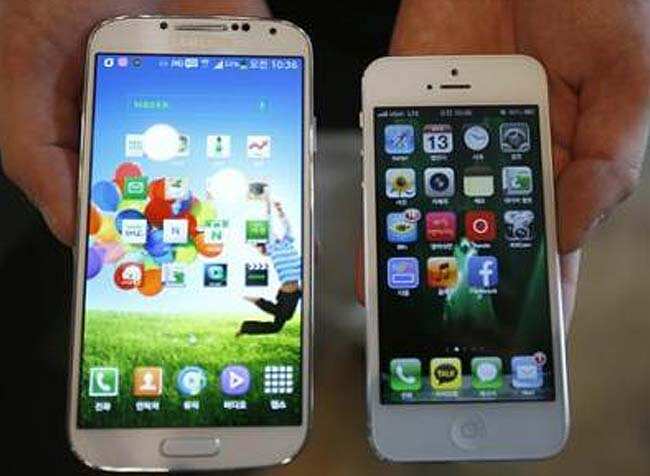 An employee of a smartphone store shows Samsung Electronics' Galaxy S4 (L) and Apple's iPhone 5 in Seoul. Credit: Reuters/Kim Hong-J)