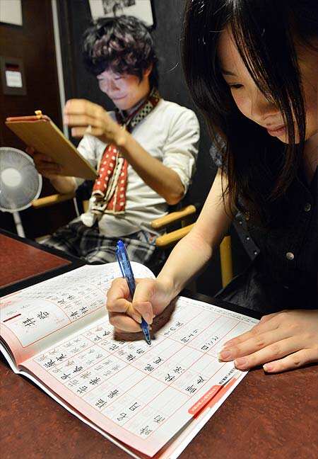 Akihiro Matsumura (L), a University student uses his tablet computer, while his friend parctices hand writing of Chinese characters on a copybook in Tokyo. AFP Photo: AFP / Yoshikazu TSUNO
</div) Akihiro Matsumura (L), a University student uses his tablet computer, while his friend parctices hand writing of Chinese characters on a copybook in Tokyo. AFP Photo: AFP / Yoshikazu TSUNO
</div)