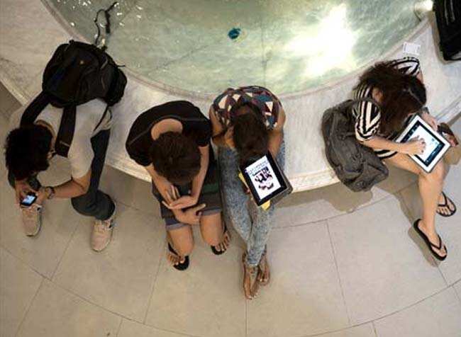 People in a mall in Bangkok use their smartphones and tablets around a fountain. AFP Photo People in a mall in Bangkok use their smartphones and tablets around a fountain. AFP Photo