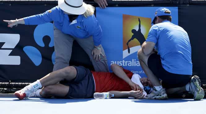 Frank Dancevic of Canada lies on the court after collapsing during his first round match against Benoit Paire of France as temperatures topped at 43 C (108 F) at the Australian Open in Melbourne. (AP Photo)