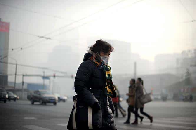 A woman wearing a face mask makes her way along a street in Beijing. China's capital was shrouded in thick smog on January 16, cutting visibility down to a few hundred metres as a count of small particulate pollution reached more than 25 times recommended levels. (AFP photo)