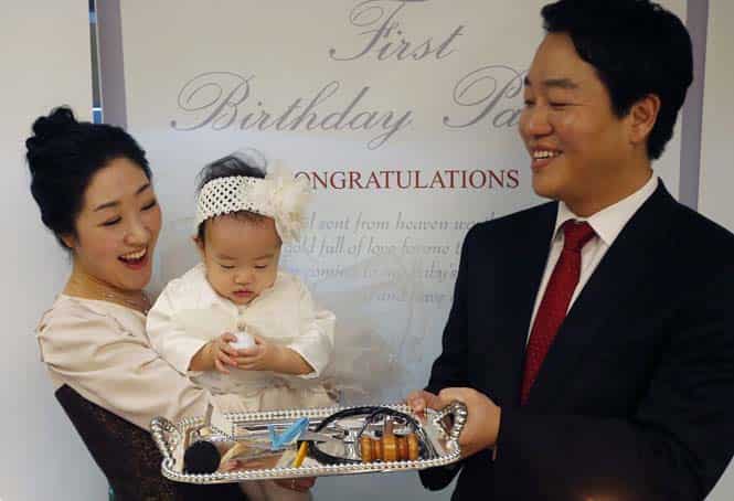 Kim Dot-byul picks up a golf ball among various items for Doljabi on a tray during her first birthday party or Doljanchi in Seoul. (Reuters photo)
</div) Kim Dot-byul picks up a golf ball among various items for Doljabi on a tray during her first birthday party or Doljanchi in Seoul. (Reuters photo)
</div)