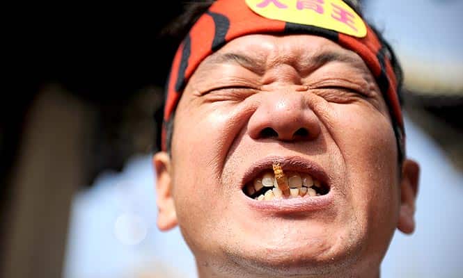 Pan Yizhong reacting as he eats worm during an eating race in Liuyang in China's central province of Hunan. (AFP)</font></strong)