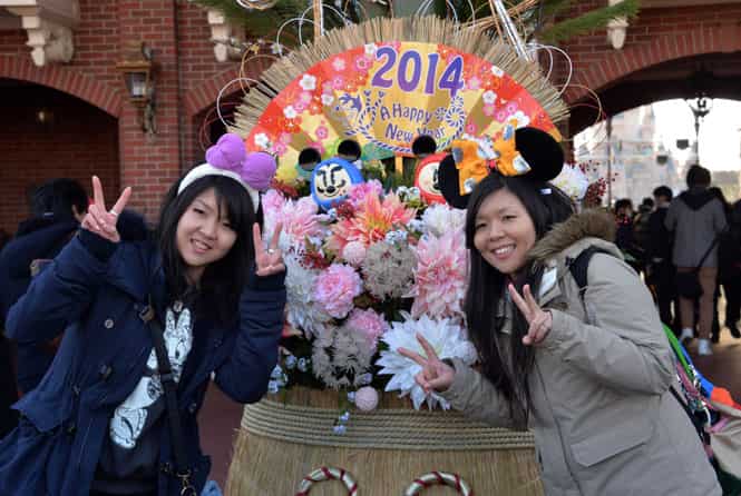 Young Japanese women pose in front of a New Year's decorations on display at Tokyo Disneyland in Urayasu, suburban Tokyo (AFP photo)</strong) Young Japanese women pose in front of a New Year's decorations on display at Tokyo Disneyland in Urayasu, suburban Tokyo (AFP photo)</strong)