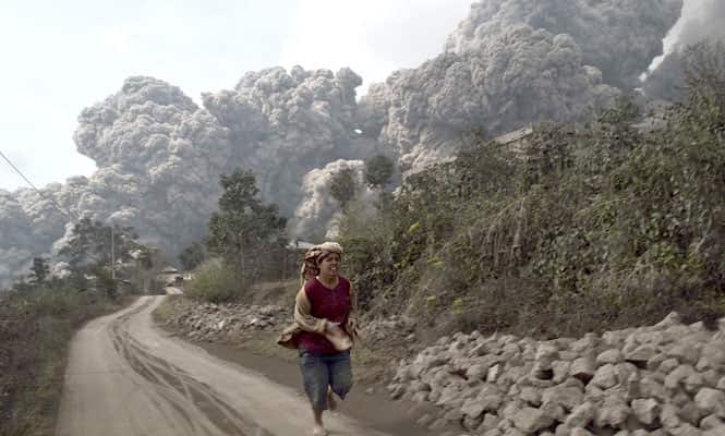 A villager runs as Mount Sinabung erupts at Sigarang-Garang village in Karo district, Indonesia's North Sumatra province. (Reuters photo) 
</div)