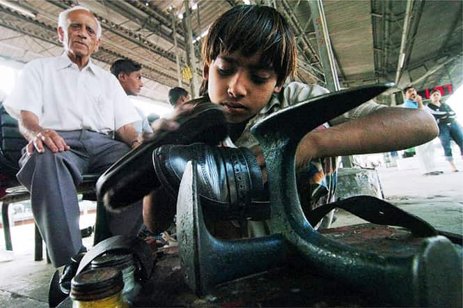 Vishal, 8, polishes shoes at the Amritsar Railway Station on the eve of 'children's day'. (AFP photo) 
</div)