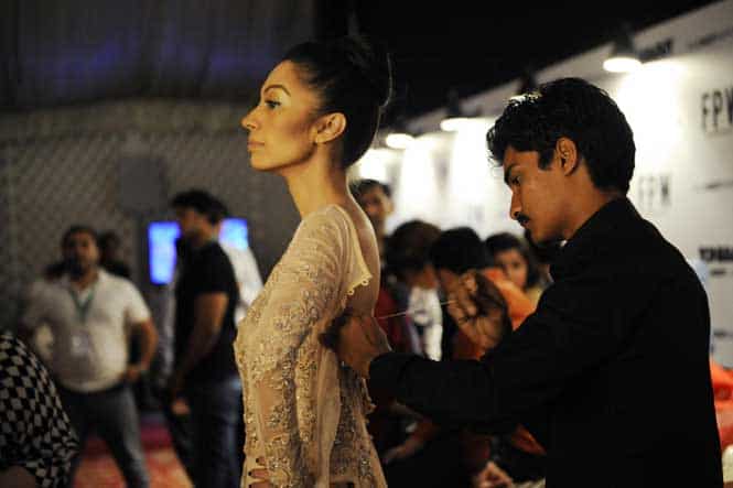 Model Rabya, wearing a creation by designer Fahad Hussayn, has her dress adjusted moments before taking the catwalk on the second day of Fashion Pakistan Week in Karachi February 20, 2014. (Reuters)</font></strong) Model Rabya, wearing a creation by designer Fahad Hussayn, has her dress adjusted moments before taking the catwalk on the second day of Fashion Pakistan Week in Karachi February 20, 2014. (Reuters)</font></strong)