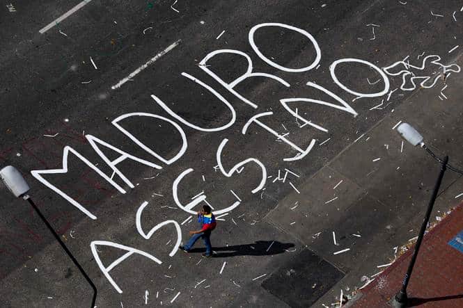 An opposition supporter walks past a words painted on a blocked street, reading 'Maduro murderer', at Altamira Square in Caracas. (Reuters photo)</strong) An opposition supporter walks past a words painted on a blocked street, reading 'Maduro murderer', at Altamira Square in Caracas. (Reuters photo)</strong)