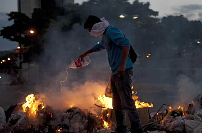 Venezuelan anti-government students light a fire during clashes with riot policemen following a protest in Caracas. (AFP photo)</strong) Venezuelan anti-government students light a fire during clashes with riot policemen following a protest in Caracas. (AFP photo)</strong)