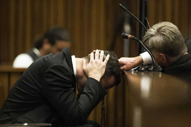 A member of his legal team reaches out to Oscar Pistorius (L) as he covers his ears with his hands while a witness gives testimony. (AFP Photo) A member of his legal team reaches out to Oscar Pistorius (L) as he covers his ears with his hands while a witness gives testimony. (AFP Photo)