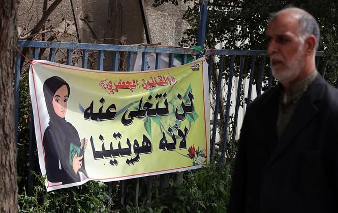 An Iraqi man walks past a banner reading in Arabic, "the Jaafari law (Jaafari Personal Status Law) we will not abandon it because it is our identity", in Baghdad. (AFP Photo)</em) An Iraqi man walks past a banner reading in Arabic, "the Jaafari law (Jaafari Personal Status Law) we will not abandon it because it is our identity", in Baghdad. (AFP Photo)</em)