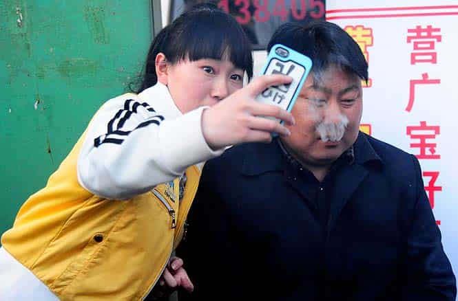 A girl clicks a selfie with a Chinese street food vendor with a resemblance to North Korean leader Kim Jong-Un in Shenyang, northeast China's Liaoning province. (AFP photo)</em)