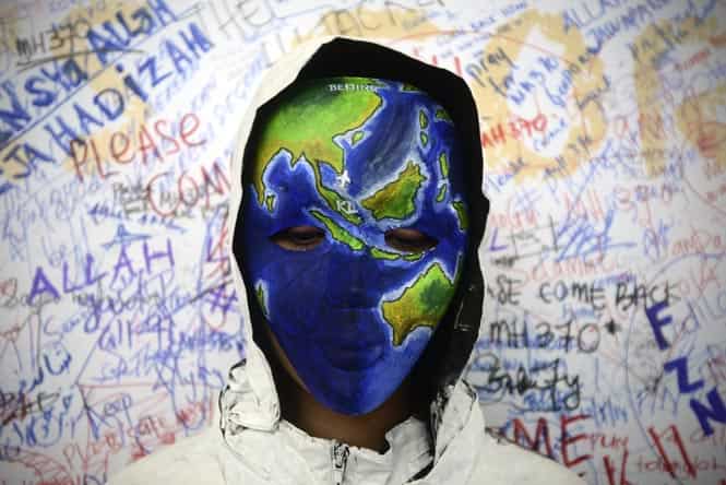 An unidentified woman with her face painted, depicting the flight of the missing Malaysia Airline poses in front of the "wall of hope" at Kuala Lumpur International Airport in Sepang. (AP photo)</em)