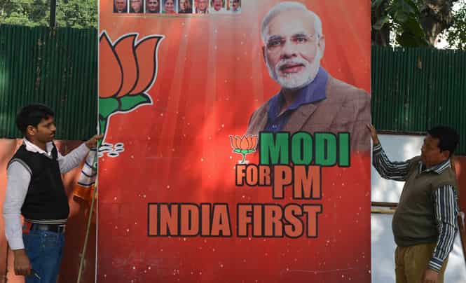 Workers erect a billboard bearing the portrait of BJP's PM candidate Narendra Modi in New Delhi. (AFP photo)</strong) Workers erect a billboard bearing the portrait of BJP's PM candidate Narendra Modi in New Delhi. (AFP photo)</strong)