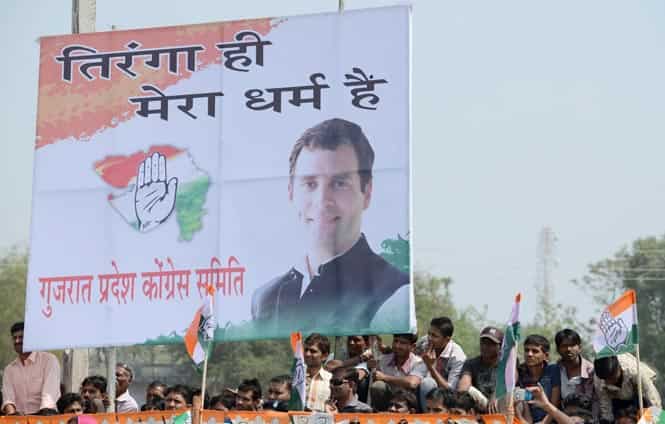 Supporters sit alongside a poster bearing the image of Rahul Gandhi as he appears at a rally at Balasinor, Ahmedabad. (AFP photo)</strong) Supporters sit alongside a poster bearing the image of Rahul Gandhi as he appears at a rally at Balasinor, Ahmedabad. (AFP photo)</strong)