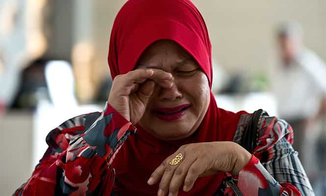 A relative of a passenger on board missing Malaysia Airlines (MAS) flight MH370 cries as she arrives at the Everly hotel in Putrajaya. (AFP Photo)</em)