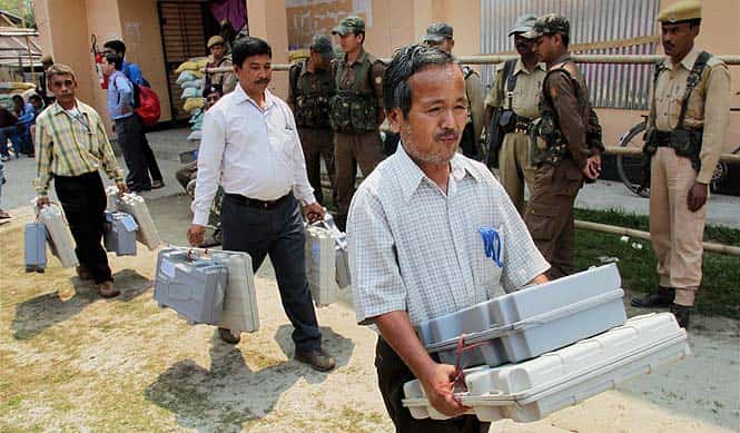 Poll officials collect Electronic Voting Machines (EVM) at a distribution center in Jorhat. (PTI Photo)</em>
</div) Poll officials collect Electronic Voting Machines (EVM) at a distribution center in Jorhat. (PTI Photo)</em>
</div)