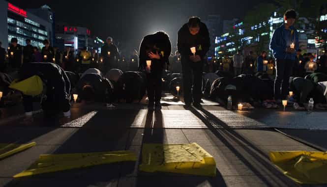 People bow as they hold candles at a vigil for students among the missing passengers of a South Korean capsized ferry, in central Ansan. (AFP Photo) People bow as they hold candles at a vigil for students among the missing passengers of a South Korean capsized ferry, in central Ansan. (AFP Photo)