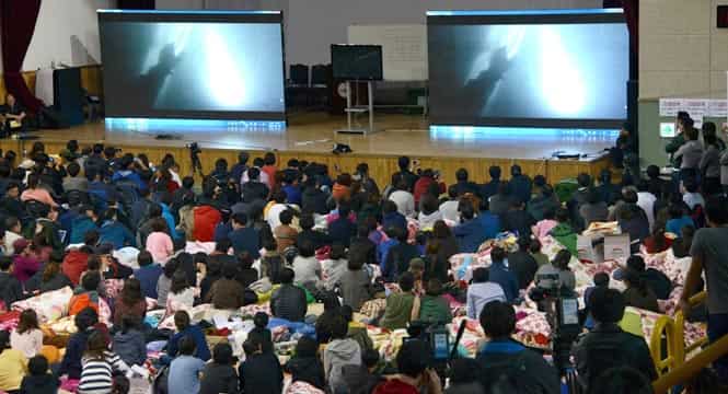 Relatives watch underwater footage of divers reaching the the sunken South Korean ferry 'Sewol' at a gymnasium used as a gathering point for family members of missing passengers, in Jindo. (AFP Photo)</em)