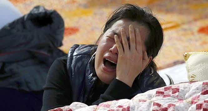 A family member of a missing passenger onboard the Sewol ferry which capsized on April 16, cries as she checks the newly announced list of the dead, at a gym in Jindo. (Reuters Photo)</em)