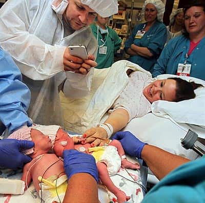 Sarah Thistlethwaite, touches her twin daughters, Jillian, center, and Jenna, for the first time while her husband, Bill, snaps photos after her delivery of the monoamniotic twin girls at Akron General Hospital (AP Photo)</em) Sarah Thistlethwaite, touches her twin daughters, Jillian, center, and Jenna, for the first time while her husband, Bill, snaps photos after her delivery of the monoamniotic twin girls at Akron General Hospital (AP Photo)</em)